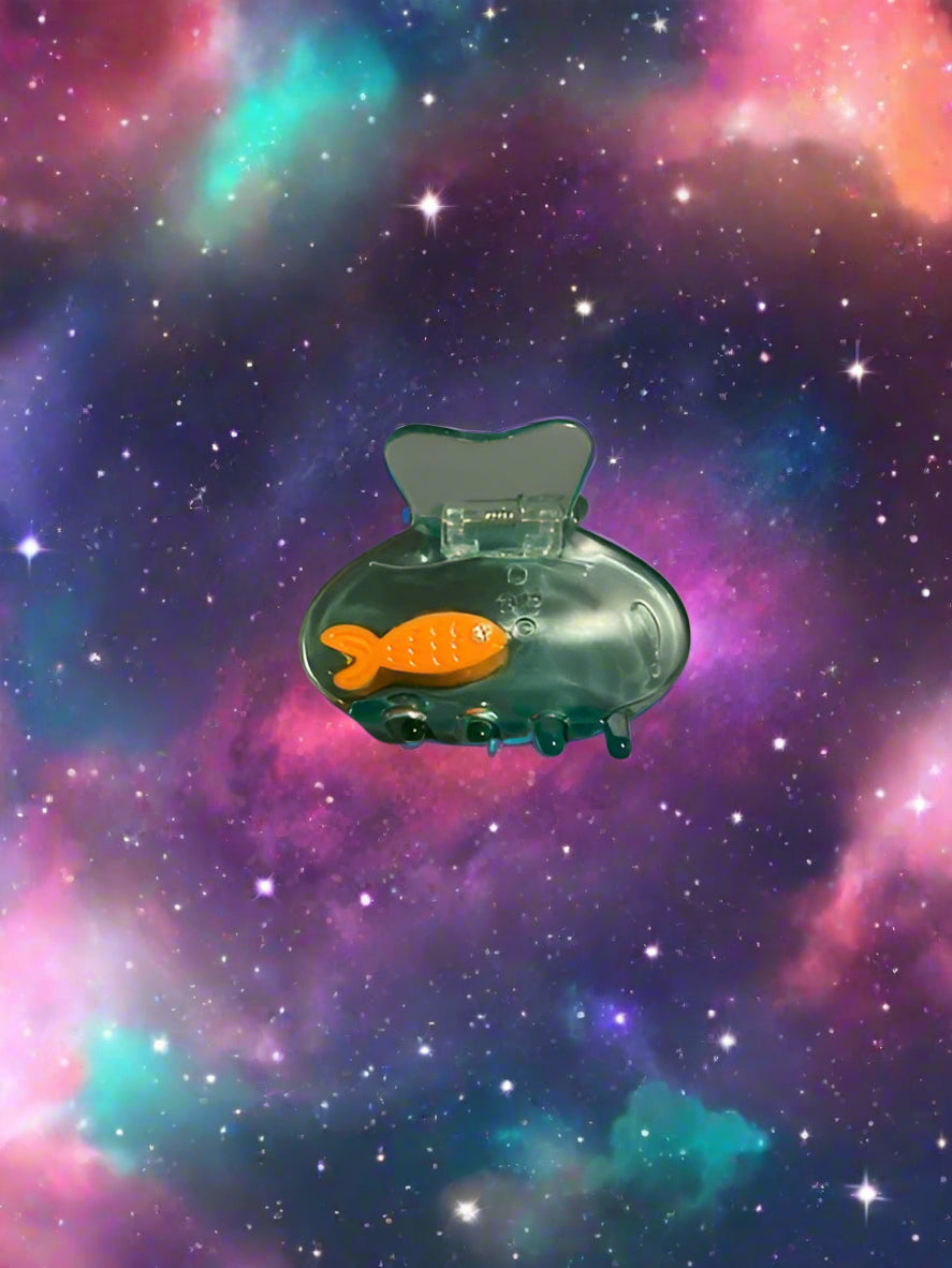 Clear plastic clip with orange fish-shaped attachment on a gray surface
