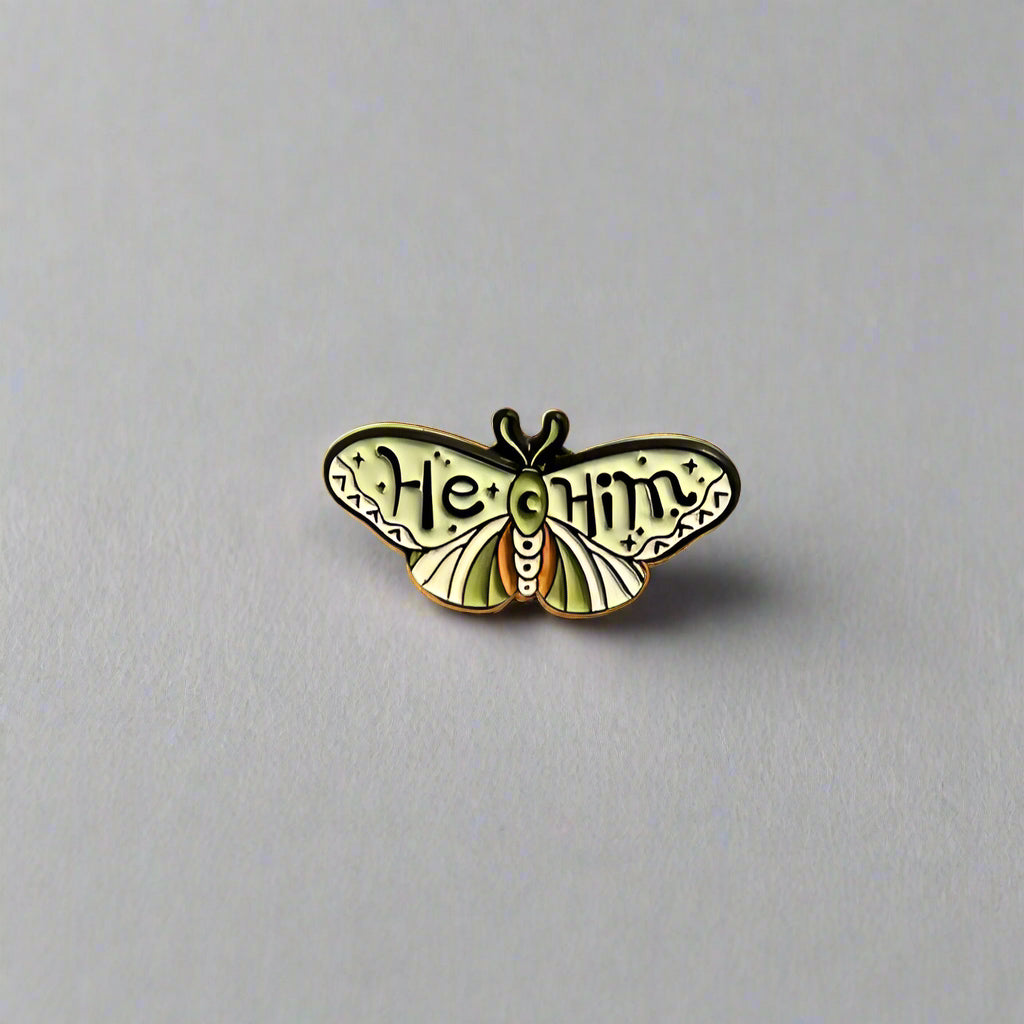 Butterfly-shaped pin with 'Heal' and 'Unity' text on a beige background