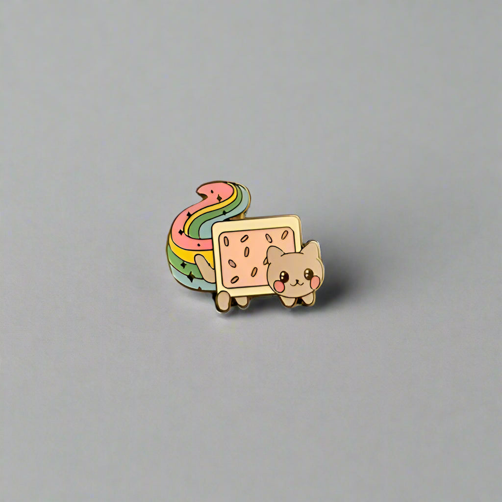 Pin with a cat design and rainbow elements on a gray surface