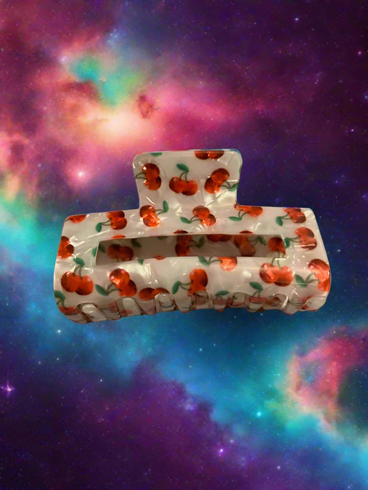 Clear hair clip with red apple pattern on a gray surface