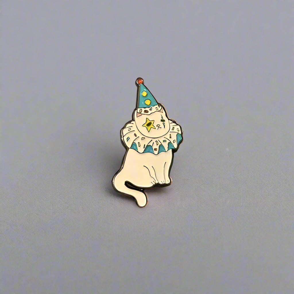Cat-shaped pin with a blue hat and yellow star on a gray background