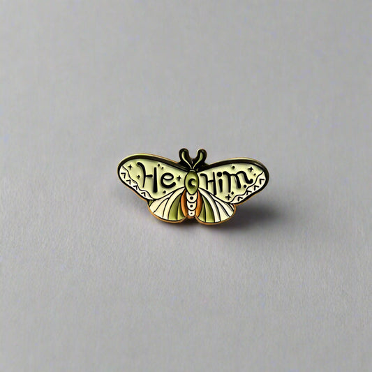 Butterfly-shaped pin with 'Heal' and 'Unity' text on a beige background