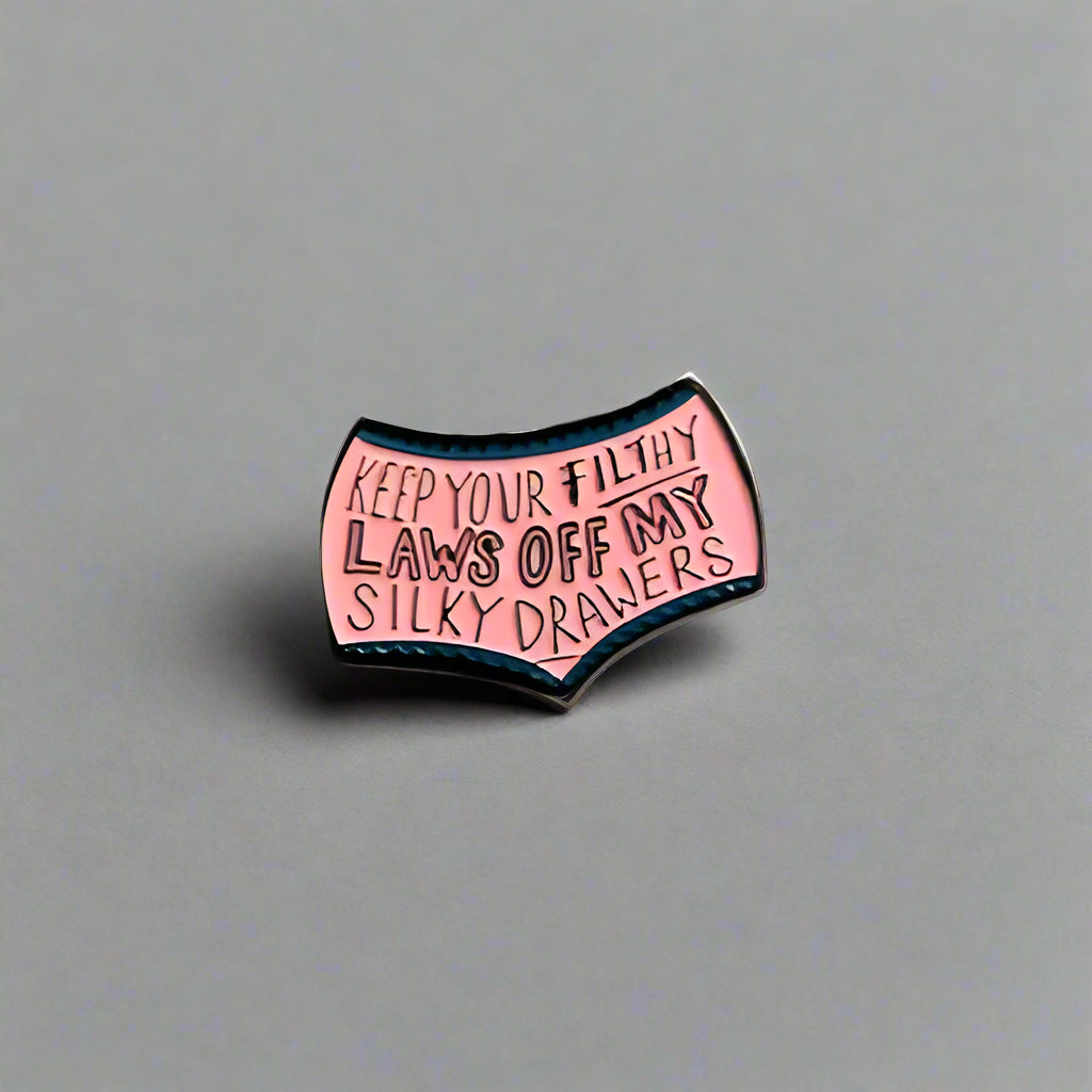 Pink enamel pin with text on a gray background