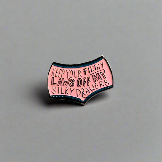 Pink enamel pin with text on a gray background