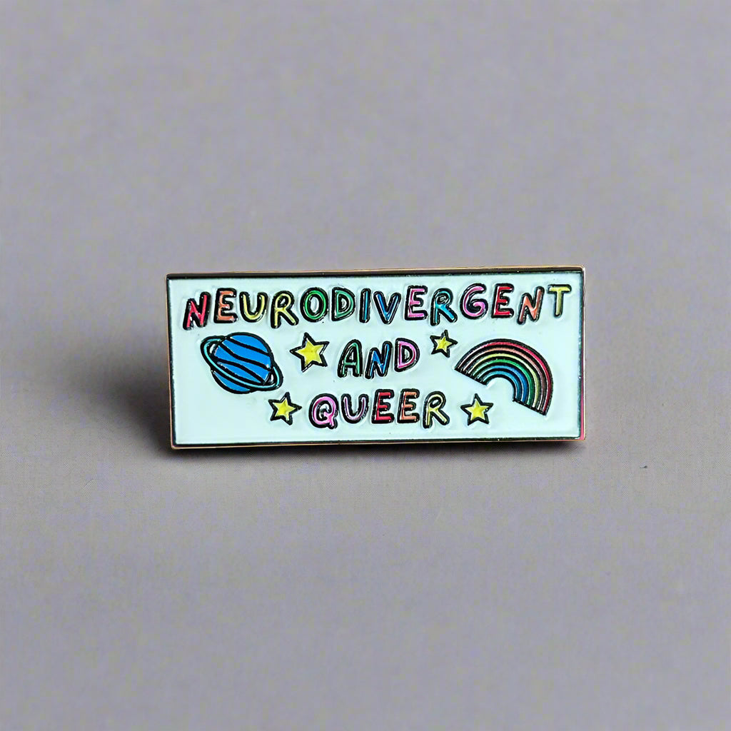 Pin with 'Neurodivergent and Queer' text on a wooden surface