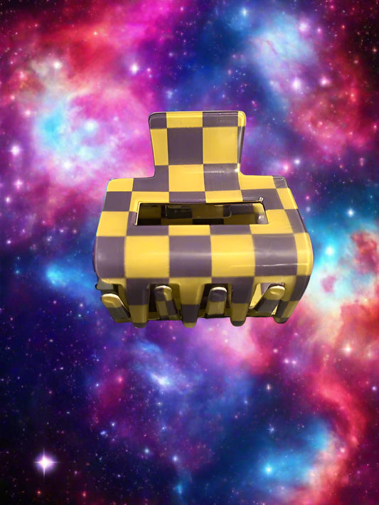 Checkered purple and yellow hair clip on a gray surface