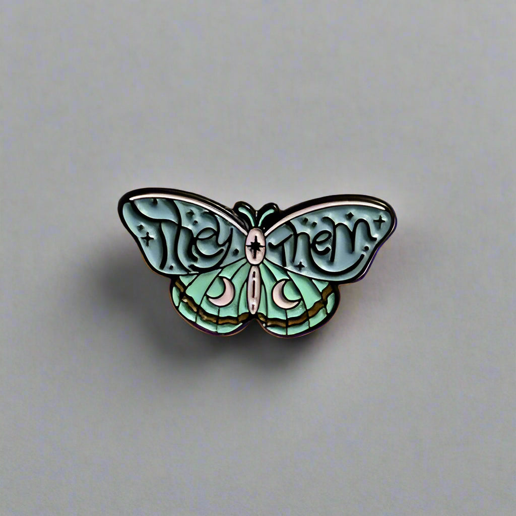 Butterfly-shaped pin with 'The Mothman' text on a beige background