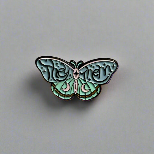 Butterfly-shaped pin with 'The Mothman' text on a beige background