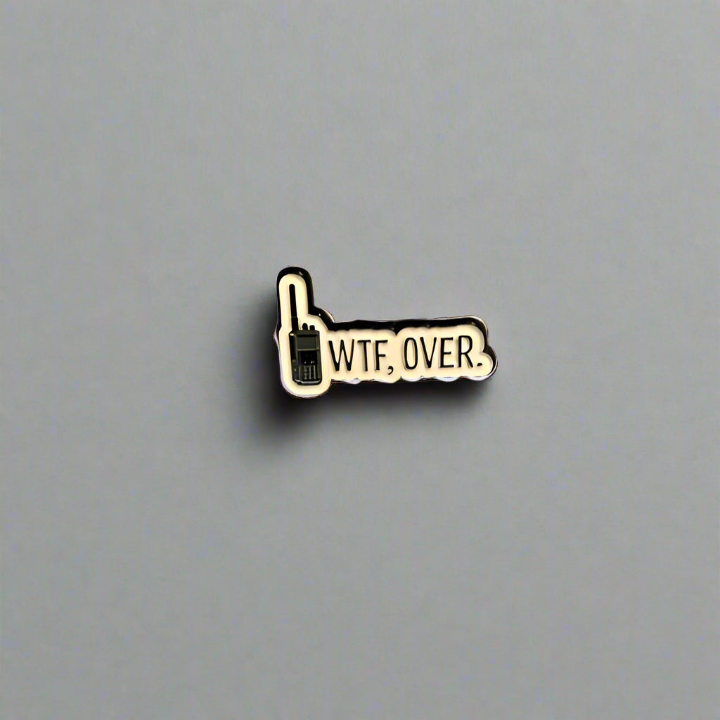Pin with 'WTF. OVER.' text on a gray surface