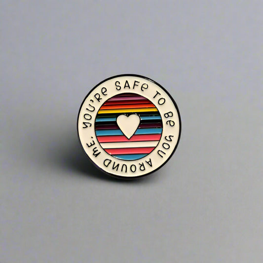 Round badge with rainbow stripes and heart symbol on a gray background